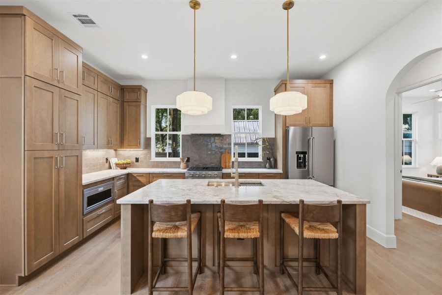 A chef's dream kitchen features warm wood cabinetry and a generously sized island with seating.
