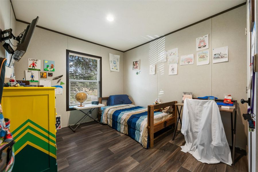 Bedroom with dark wood finished floors and ornamental molding