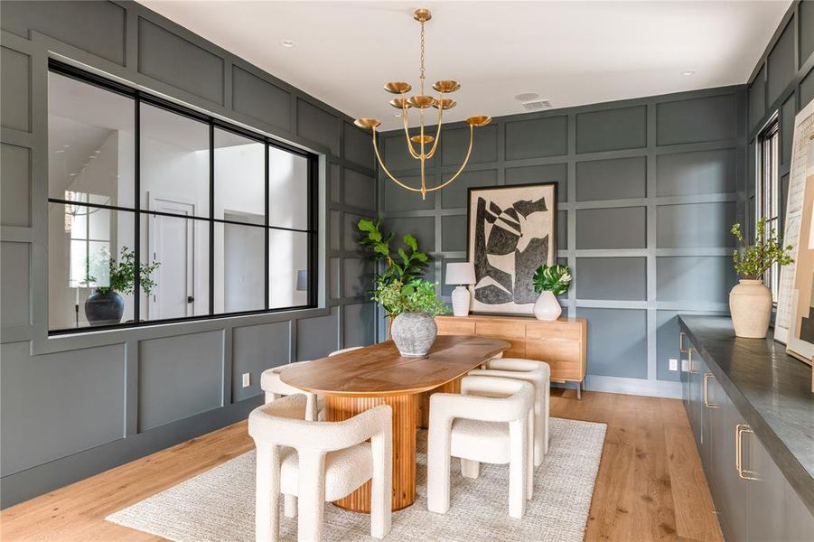 Dining room with a decorative wall, light wood-type flooring, and a chandelier