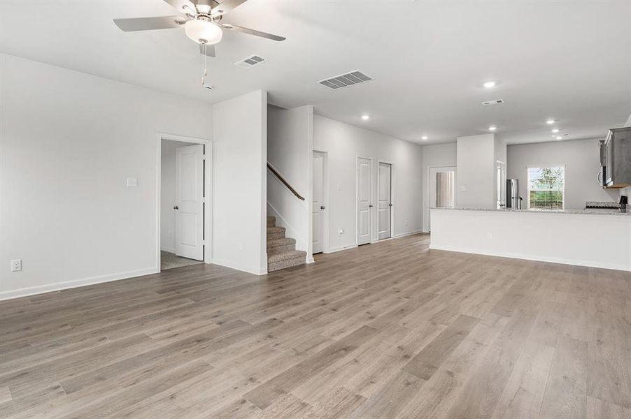 Unfurnished living room with light wood-style flooring, stairs, recessed lighting, and ceiling fan