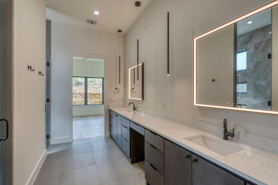 Clean lines and stone counters define this modern dual vanity bathroom with integrated lighting. Clean lines and stone counters define this modern dual vanity bathroom with integrated lighting.