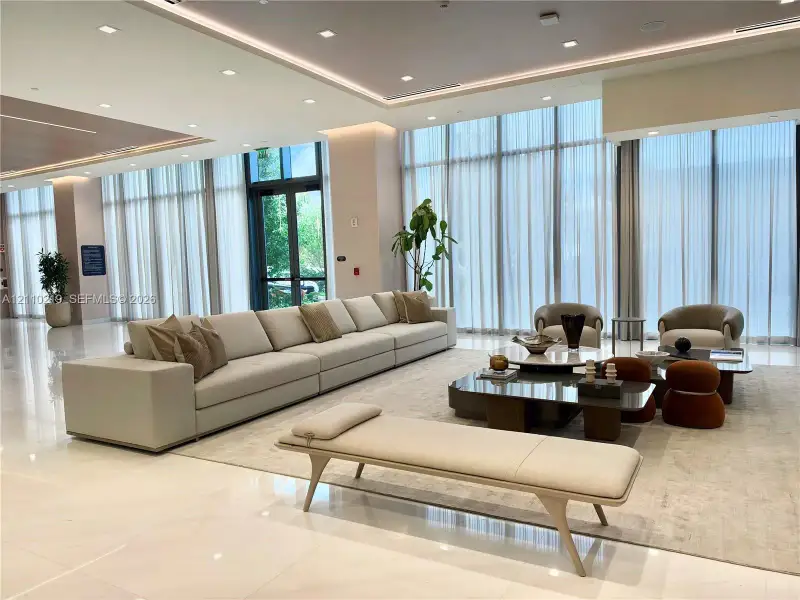 Expansive lobby featuring floor-to-ceiling windows, polished stone flooring, recessed ceiling lighting, and cove accent lighting