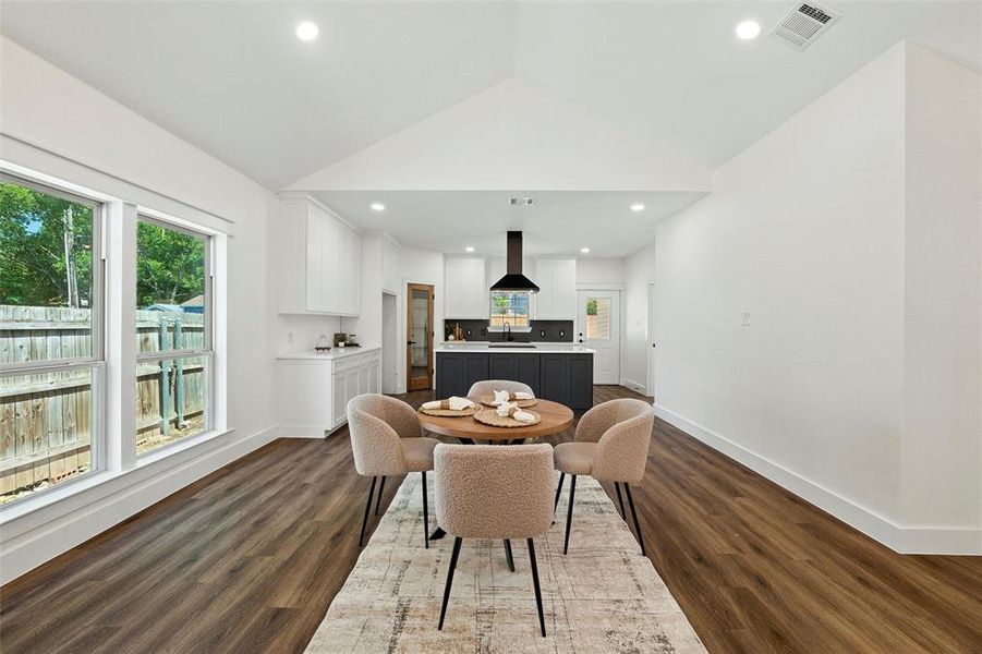 Dining area featuring lofted ceiling, dark wood-style flooring, and recessed lighting