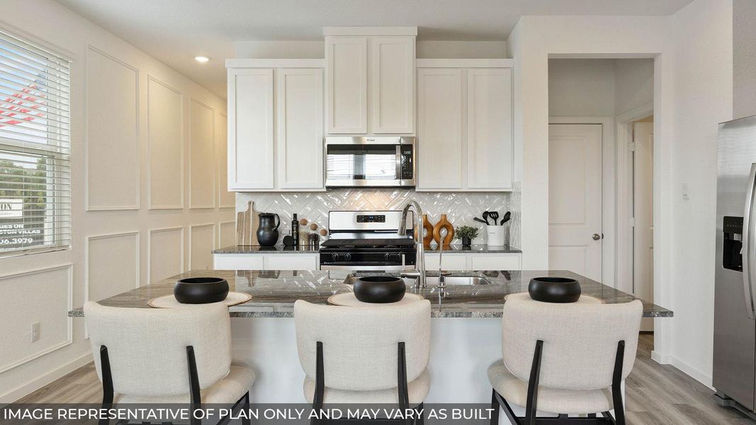 Kitchen featuring white cabinetry, stainless steel appliances, a tile backsplash, and an island with a built-in sink and seating