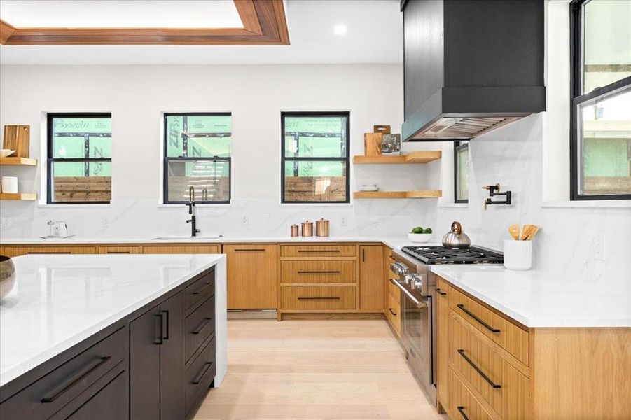 Kitchen with plenty of natural light, range with two ovens, and wall chimney exhaust hood