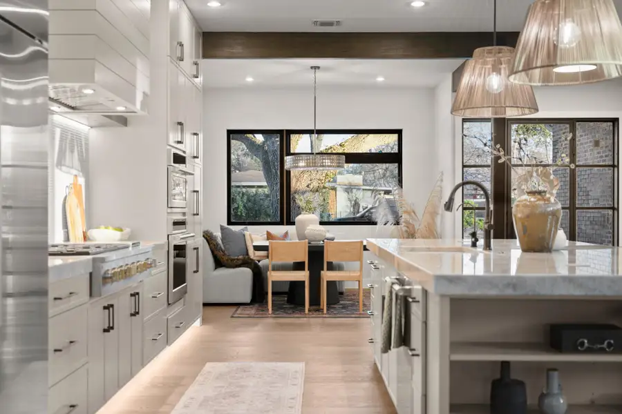 Kitchen with beamed ceiling, light stone counters, pendant lighting, stainless steel appliances, and recessed lighting