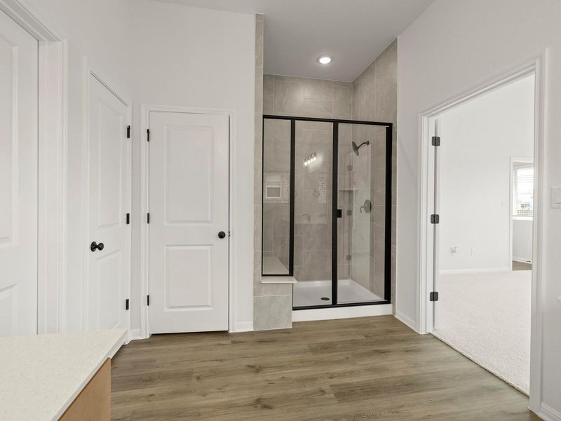 Walk-in shower with clear glass enclosure and black hardware, surrounded by large format tile