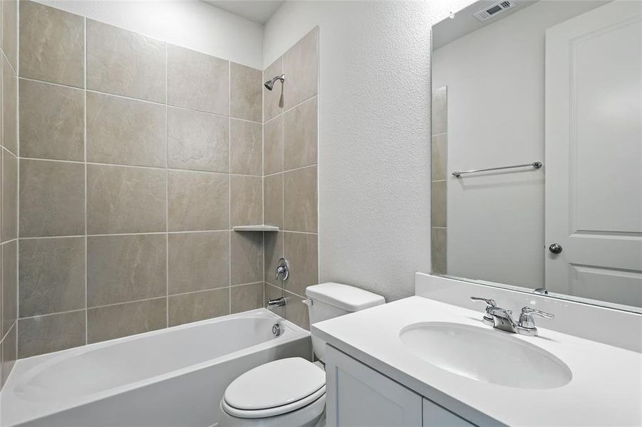 Bathroom featuring a textured wall, tub / shower combination, and vanity