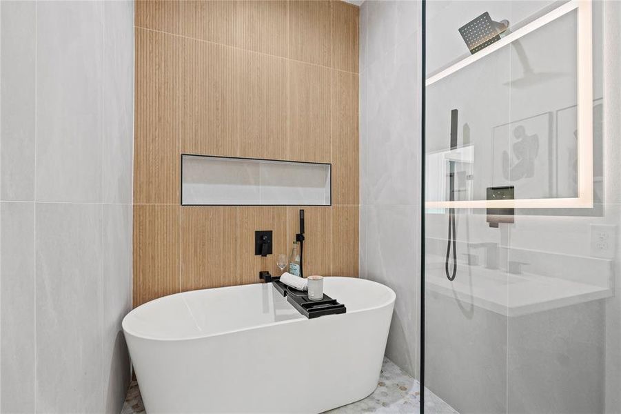 Full bathroom featuring a walk in shower, a soaking tub, and tile walls