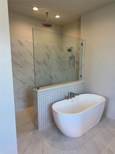 Luxurious bath with freestanding soaking tub, oversized walk-in shower, rainfall showerhead, and designer tile finishes.