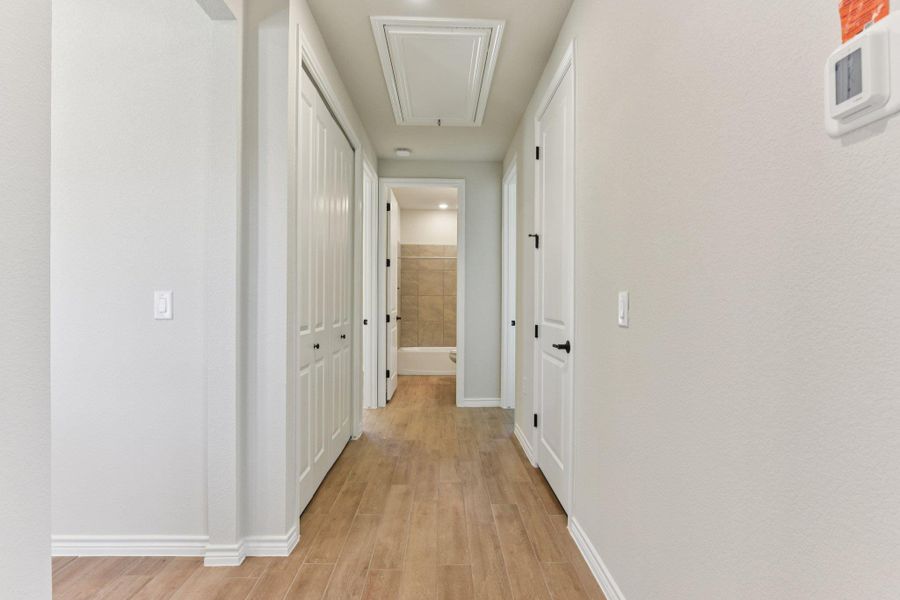 Corridor featuring attic access and light wood-style floors