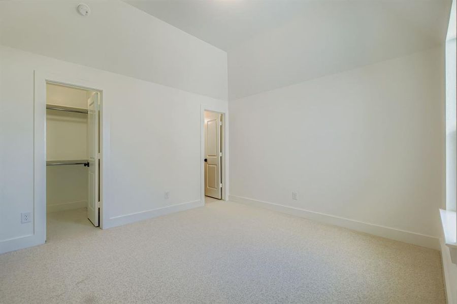Unfurnished bedroom featuring a walk in closet and light colored carpet Unfurnished bedroom featuring a walk in closet and light colored carpet