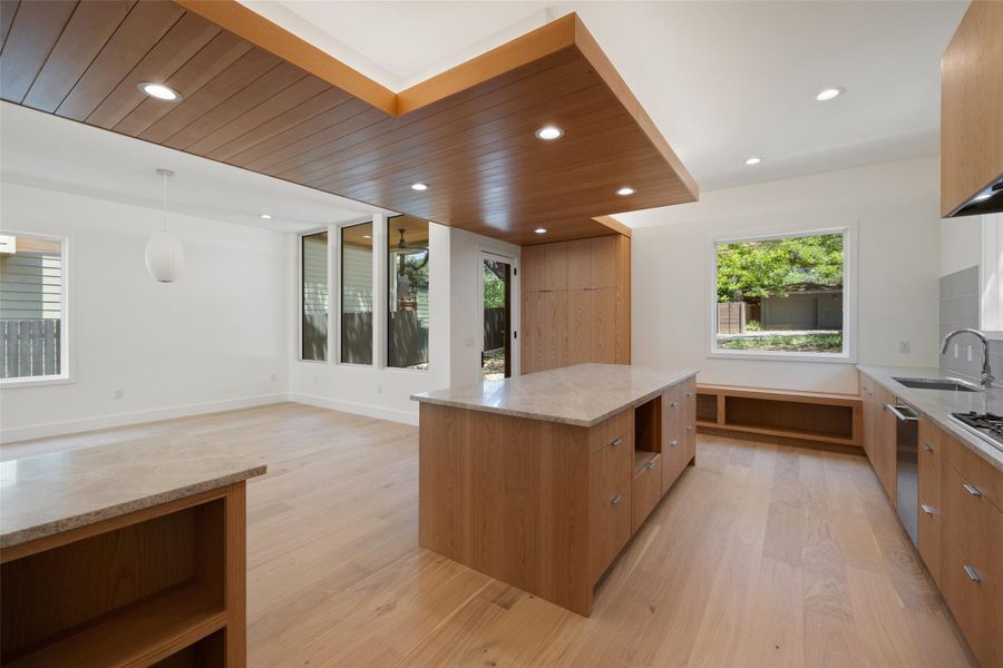 Kitchen featuring plenty of natural light, modern cabinets, light stone countertops, light wood-style floors, and recessed lighting Kitchen featuring plenty of natural light, modern cabinets, light stone countertops, light wood-style floors, and recessed lighting
