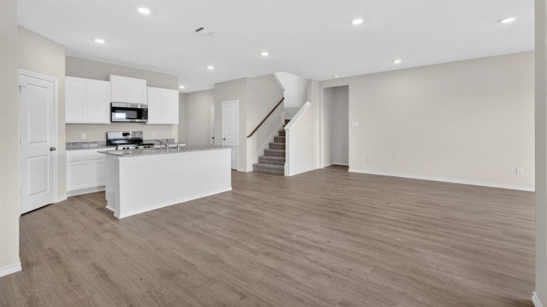 Open-concept living area featuring wood-finish flooring, recessed lighting, and a neutral color palette