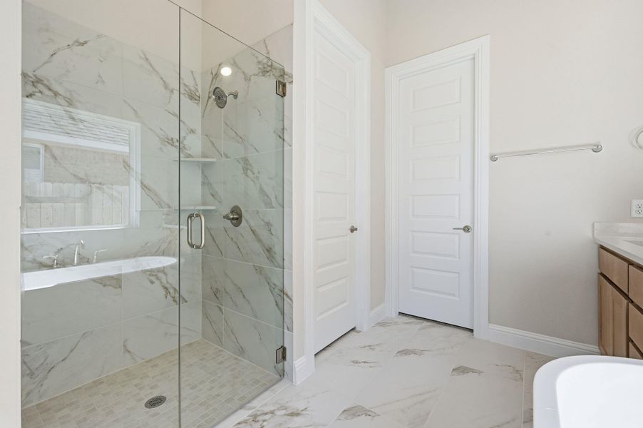 Full bathroom featuring a freestanding tub, vanity, light marble finish flooring, and a marble finish shower Full bathroom featuring a freestanding tub, vanity, light marble finish flooring, and a marble finish shower