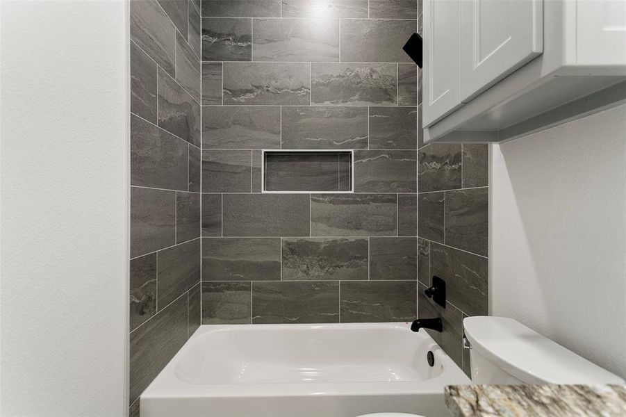 Bathroom with toilet and tiled shower / bath