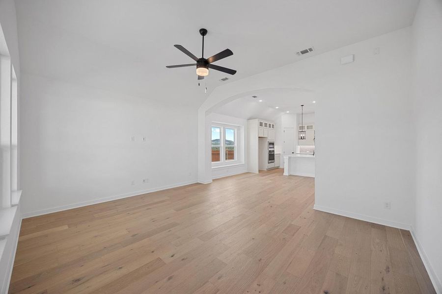 Unfurnished living room featuring a ceiling fan, vaulted ceiling, light wood-style flooring, arched walkways, and recessed lighting