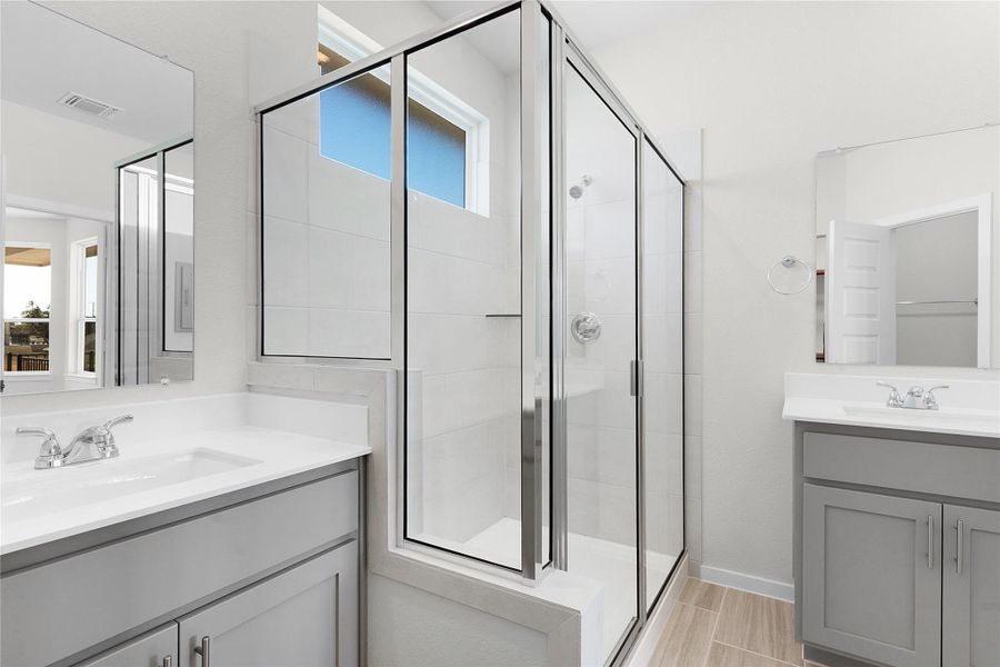 Full bath featuring a shower stall and two vanities