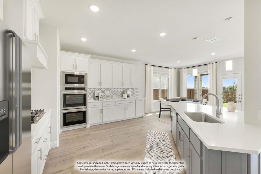 Kitchen with white cabinets, gray island, double wall ovens, and stainless steel appliances on light wood floors