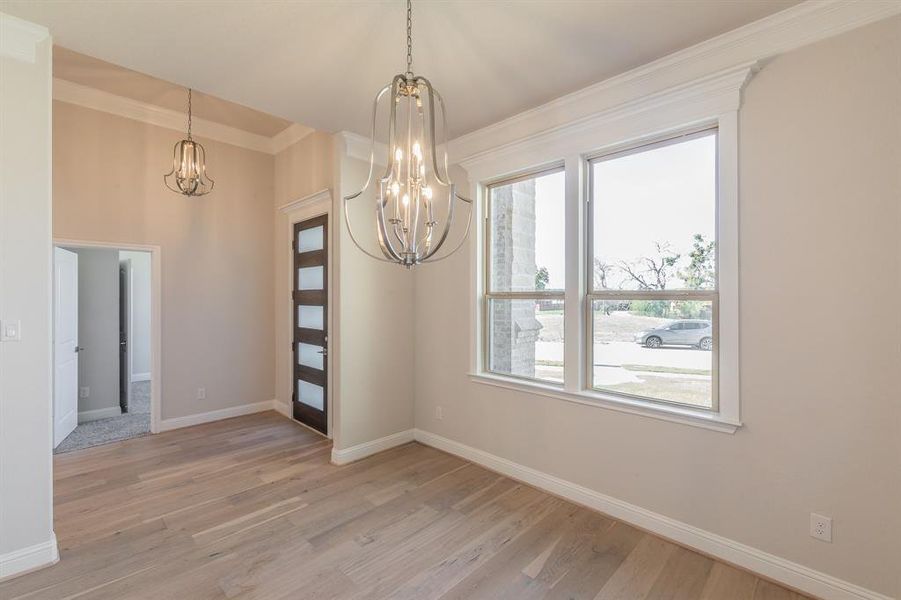 Unfurnished dining area with light wood-type flooring, ornamental molding, and a chandelier