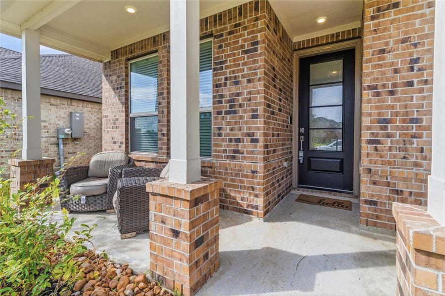 Charming brick front porch with cozy wicker seating and a welcoming entryway, perfect for relaxing and greeting guests. Charming brick front porch with cozy wicker seating and a welcoming entryway, perfect for relaxing and greeting guests.