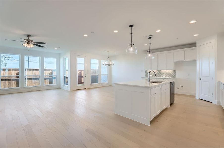 Kitchen featuring sink, an island with sink, pendant lighting, and light wood-type flooring