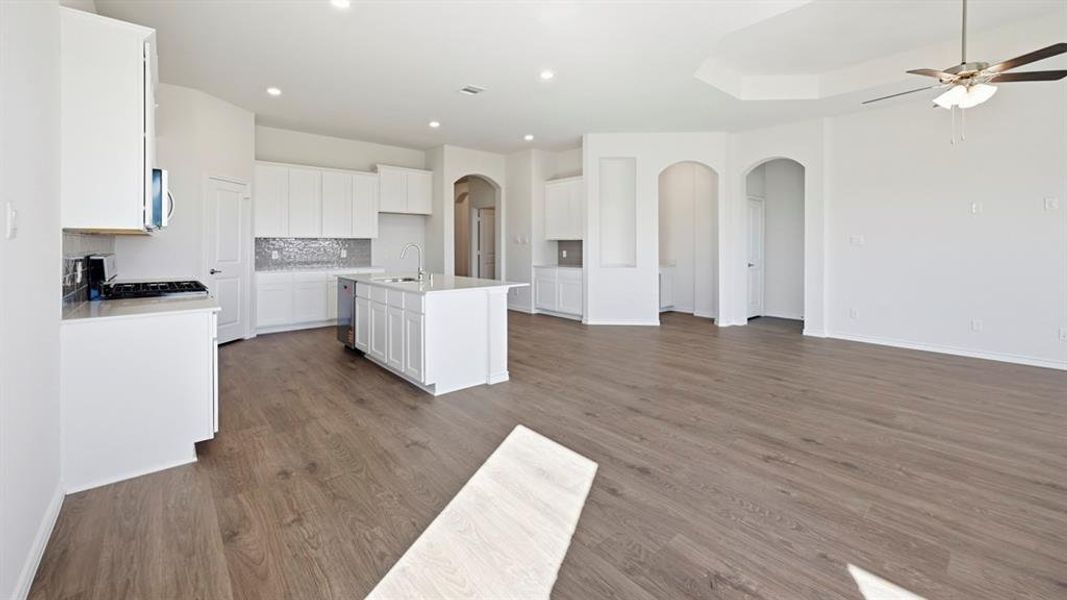 Open-concept living area featuring wood-finish flooring, recessed lighting, and a tray ceiling with a ceiling fan