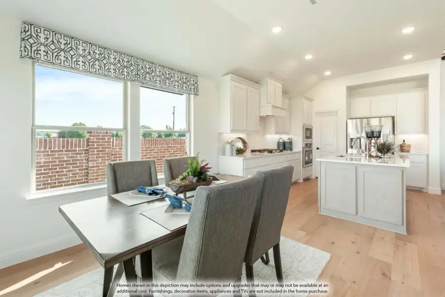 Open dining area with gray chairs flows into white kitchen with island and hardwood floors
