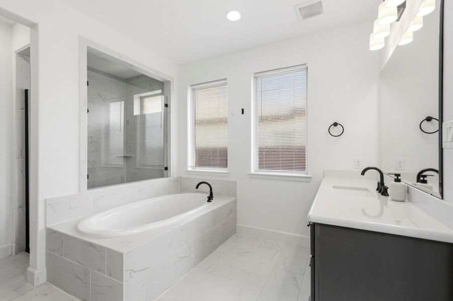 The spacious walk-in shower features modern tile extending from floor to ceiling, creating a spa-inspired feel while offering durability and easy maintenance.