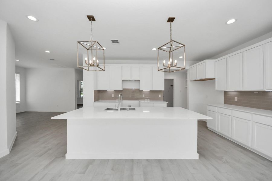The kitchen is a culinary haven, featuring granite countertops, a tile backsplash, stainless steel appliances, 42” upper cabinets, and undercabinet lighting. Sample photo of completed home with similar floor plan. Actual colors and selections may vary. The kitchen is a culinary haven, featuring granite countertops, a tile backsplash, stainless steel appliances, 42” upper cabinets, and undercabinet lighting. Sample photo of completed home with similar floor plan. Actual colors and selections may vary.
