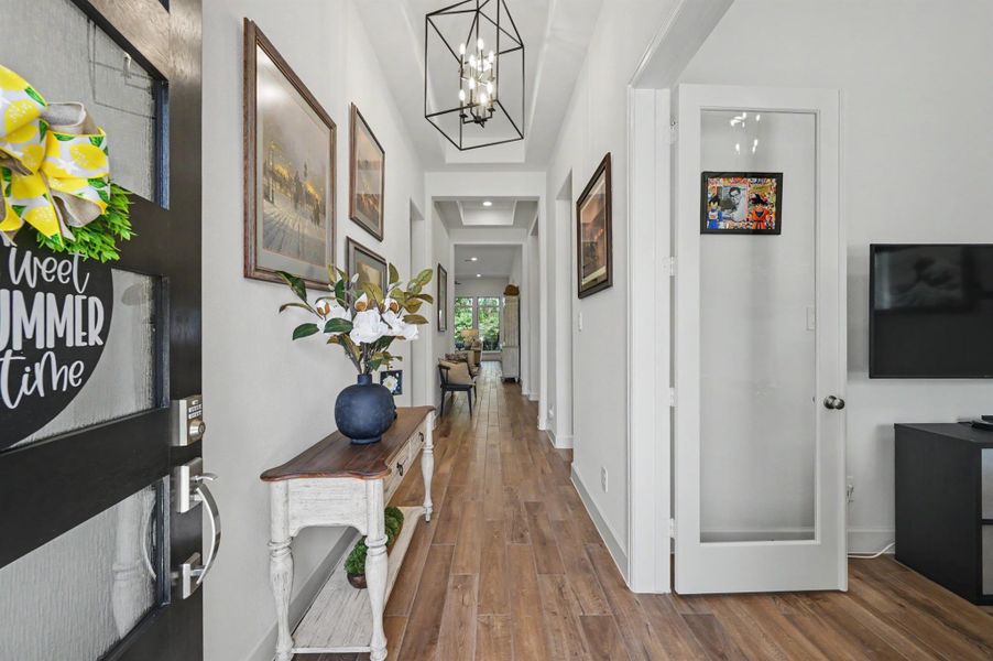 As you enter the home, you are welcomed by high ceilings and upgraded wood-look tile flooring in medium brown tones. There is a tray ceiling in the entry, and the lighting upgraded with this chandelier. The study is located to the right through the double French doors. As you enter the home, you are welcomed by high ceilings and upgraded wood-look tile flooring in medium brown tones. There is a tray ceiling in the entry, and the lighting upgraded with this chandelier. The study is located to the right through the double French doors.