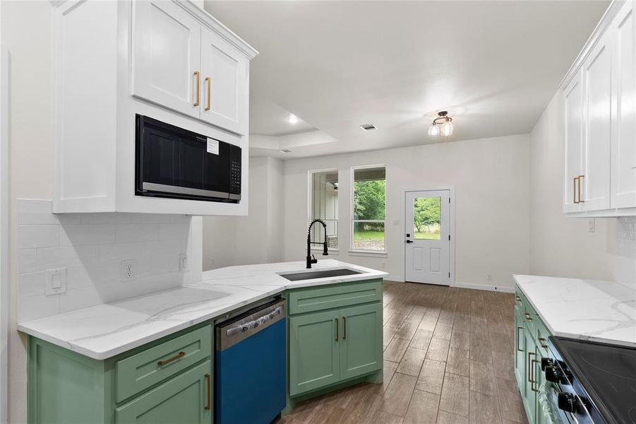 Modern kitchen featuring white upper cabinetry, green lower cabinetry, and light-toned countertops