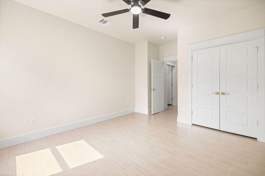 Unfurnished bedroom with visible vents, baseboards, light wood-style flooring, ceiling fan, and a closet