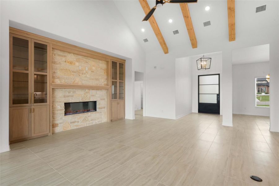 A spacious living room showcases a striking stone fireplace, built-in cabinetry, and vaulted ceilings with exposed beams. A spacious living room showcases a striking stone fireplace, built-in cabinetry, and vaulted ceilings with exposed beams.