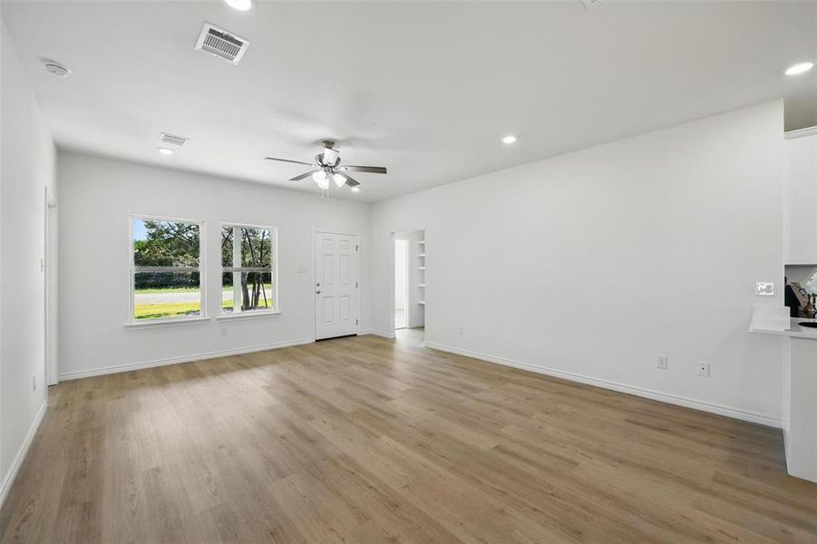Unfurnished living room featuring ceiling fan, light wood finished floors, baseboards, and recessed lighting Unfurnished living room featuring ceiling fan, light wood finished floors, baseboards, and recessed lighting