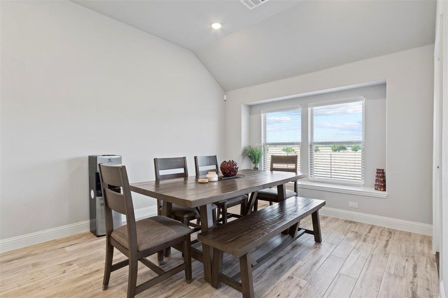 Dining space with vaulted ceiling and light hardwood / wood-style floors