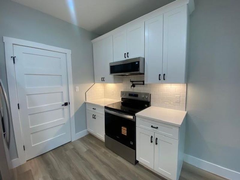 A compact culinary space features modern white cabinetry and essential appliances for efficient living. A compact culinary space features modern white cabinetry and essential appliances for efficient living.