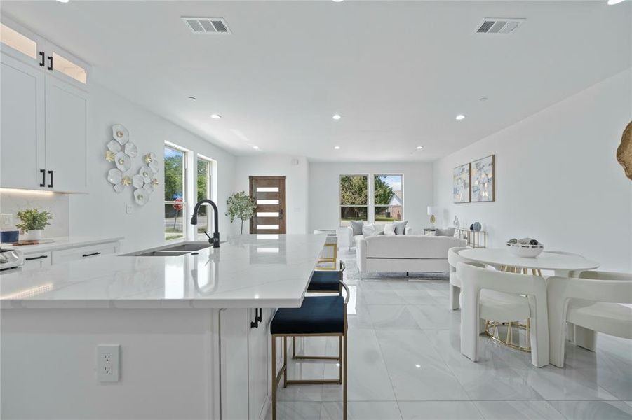 Kitchen featuring a sink, white cabinets, light stone counters, plenty of natural light, and recessed lighting