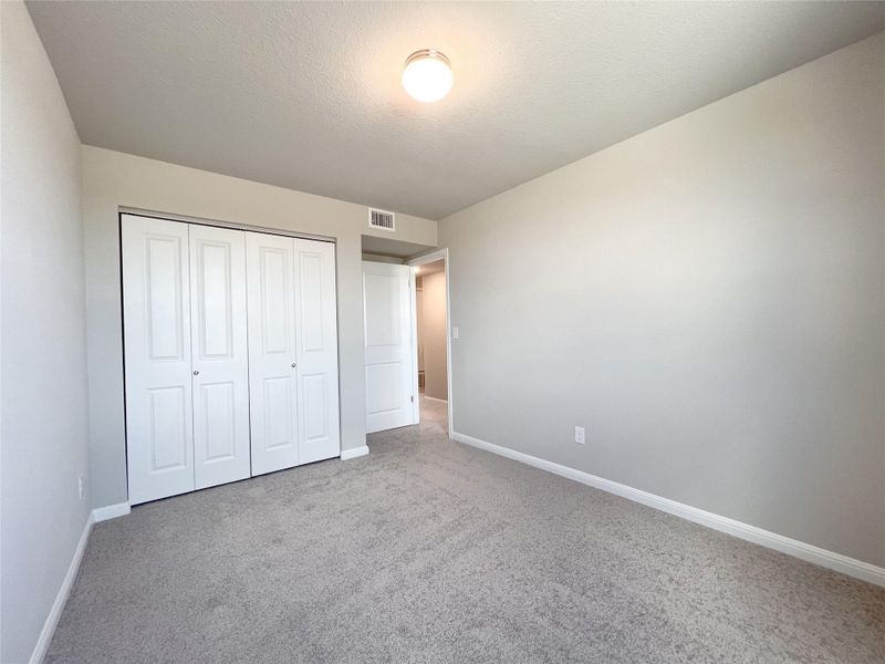 Unfurnished bedroom featuring carpet flooring, a textured ceiling, and a closet