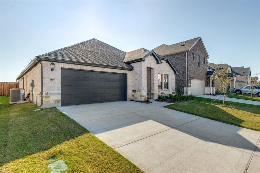 French country style house featuring roof with shingles, a garage, brick siding, and driveway