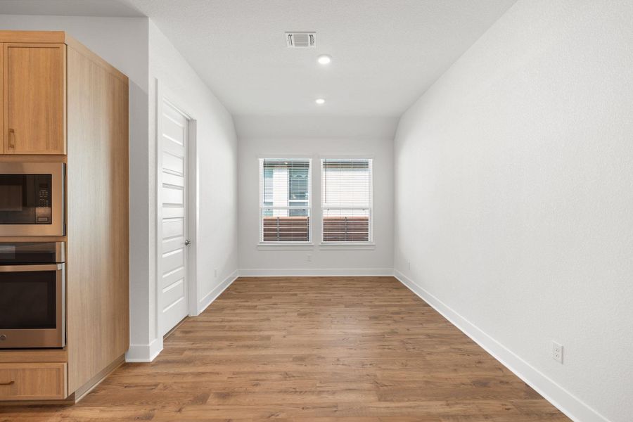 A well-lit, open-concept living area boasts rich hardwood flooring and large windows, creating an inviting atmosphere.