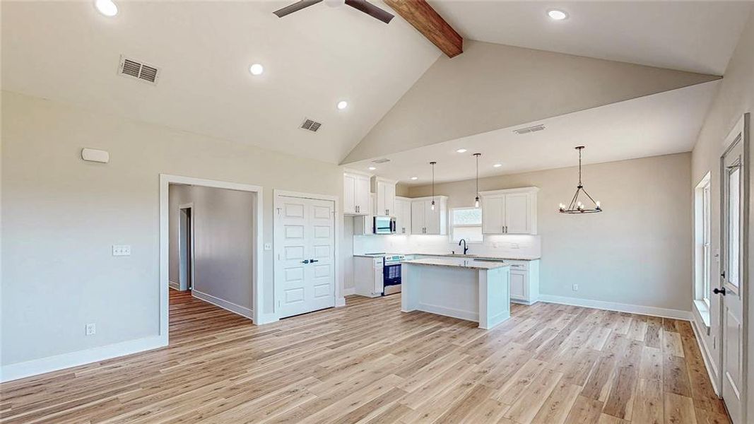 Kitchen featuring beamed ceiling, a kitchen island, light wood-type flooring, white cabinetry, and light countertops Kitchen featuring beamed ceiling, a kitchen island, light wood-type flooring, white cabinetry, and light countertops