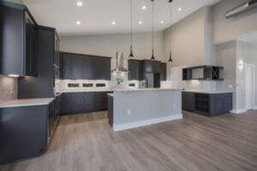 Kitchen with decorative backsplash, pendant lighting, wood finished floors, and light countertops