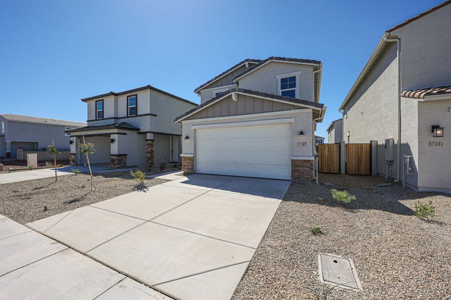 A driveway with a garage and a house in the background. A driveway with a garage and a house in the background.