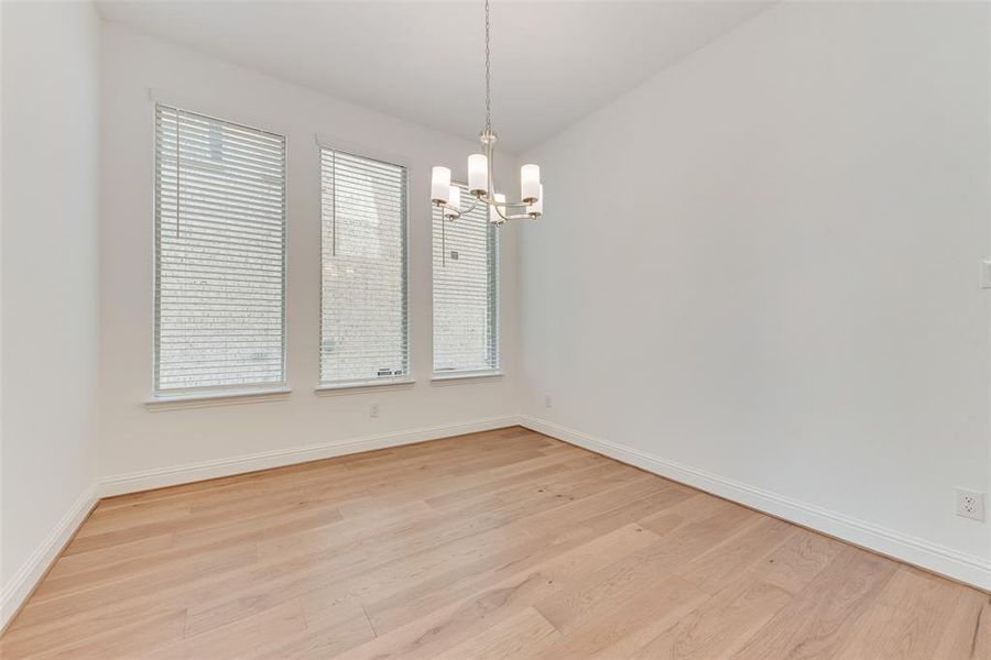 Empty room with an inviting chandelier, light hardwood / wood-style flooring, and a healthy amount of sunlight