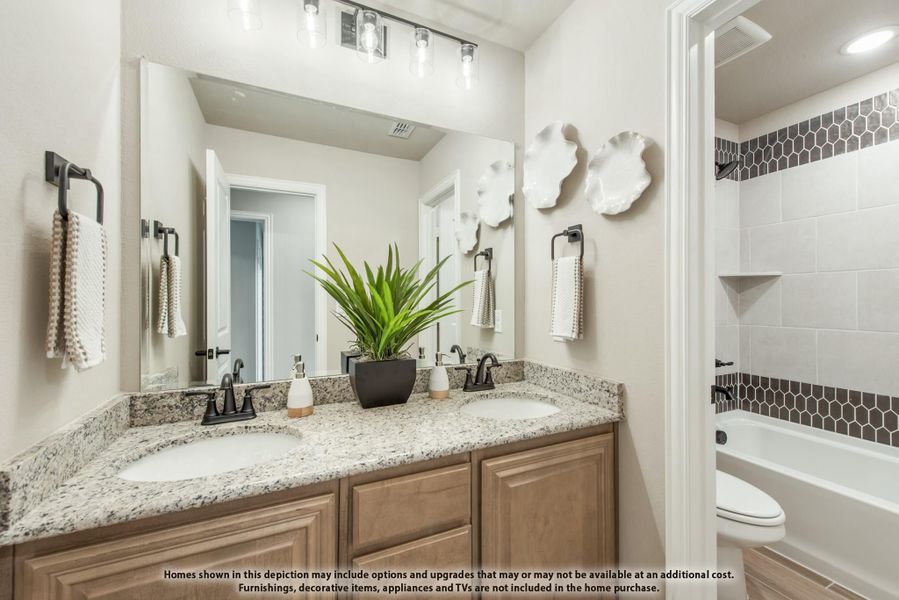Bathroom with double sink granite vanity, large mirror, and tiled shower-tub combo with dark accent tiles