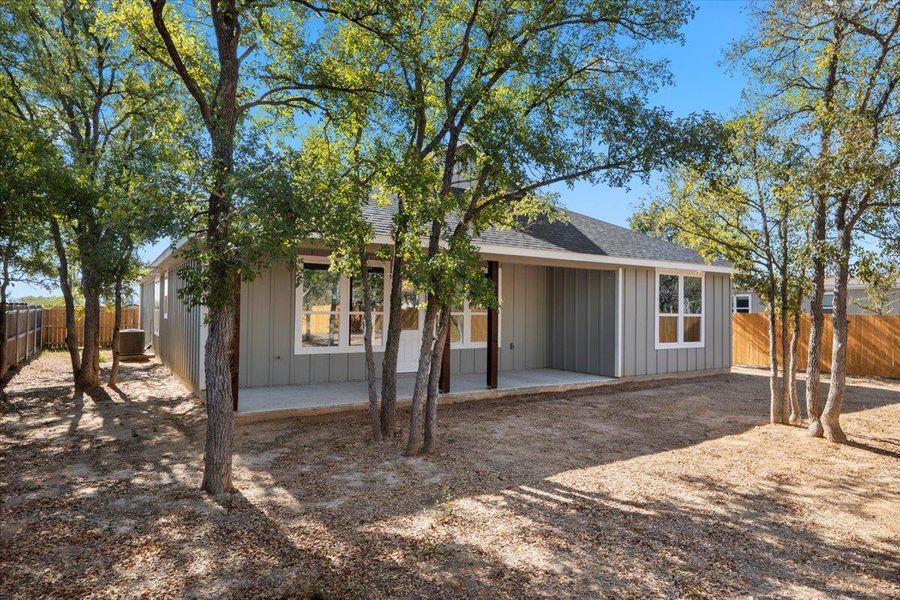 Rear view of property featuring a fenced backyard, board and batten siding, a patio area, and a shingled roof