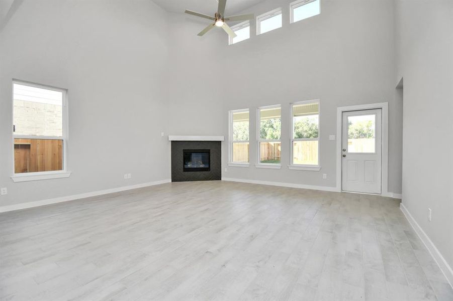 Family room flooded with natural light through the expansive windows. The premium tile flooring adds a touch of luxury to the space, creating the perfect setting for relaxing moments and cherished gatherings with loved ones.