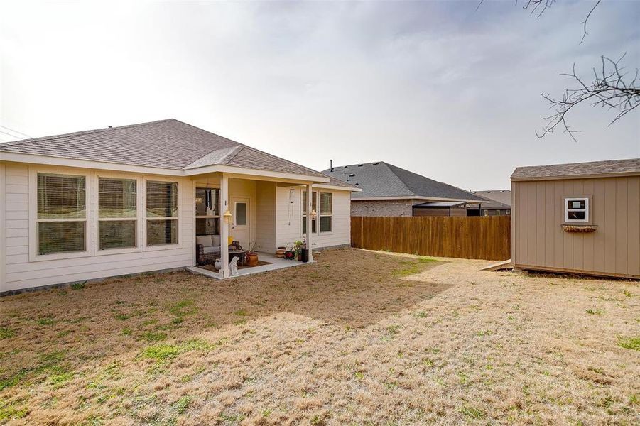 Rear view of house with roof with shingles, a patio, a storage unit, fence, and an outdoor structure