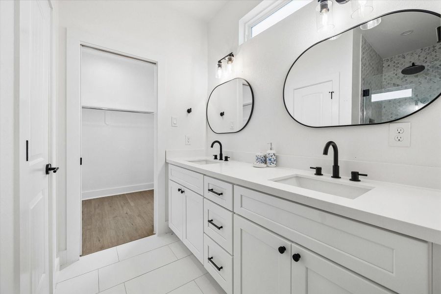 Dual sinks and quartz counters mean nobody waits their turn in the morning. Rounded mirrors and black faucets keep the primary bath feeling current. Dual sinks and quartz counters mean nobody waits their turn in the morning. Rounded mirrors and black faucets keep the primary bath feeling current.